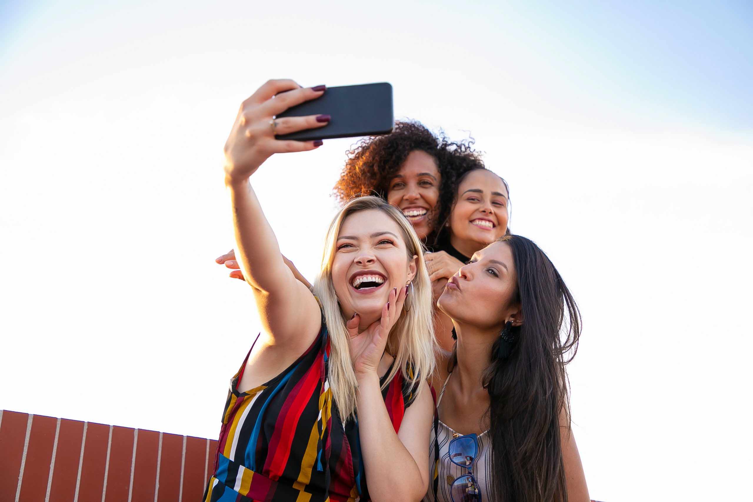 A group of young women smiling and taking a selfie to capture the feel good moment and celebrate each other.