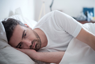 Depressed man lying on his side in his bed