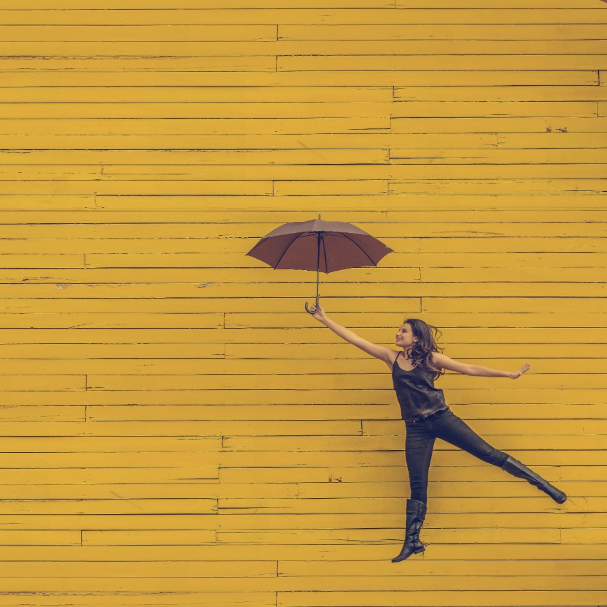 young woman leaping with an umbrella on her hand