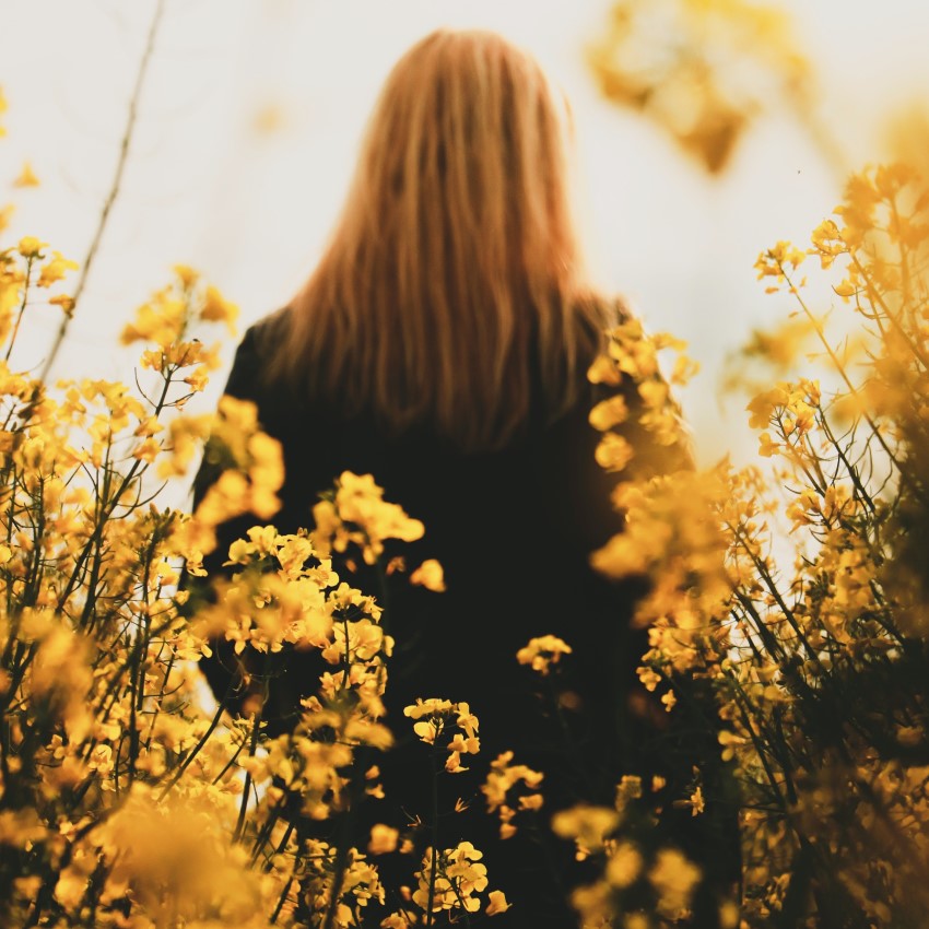 woman in the middle of a flower field focused in life